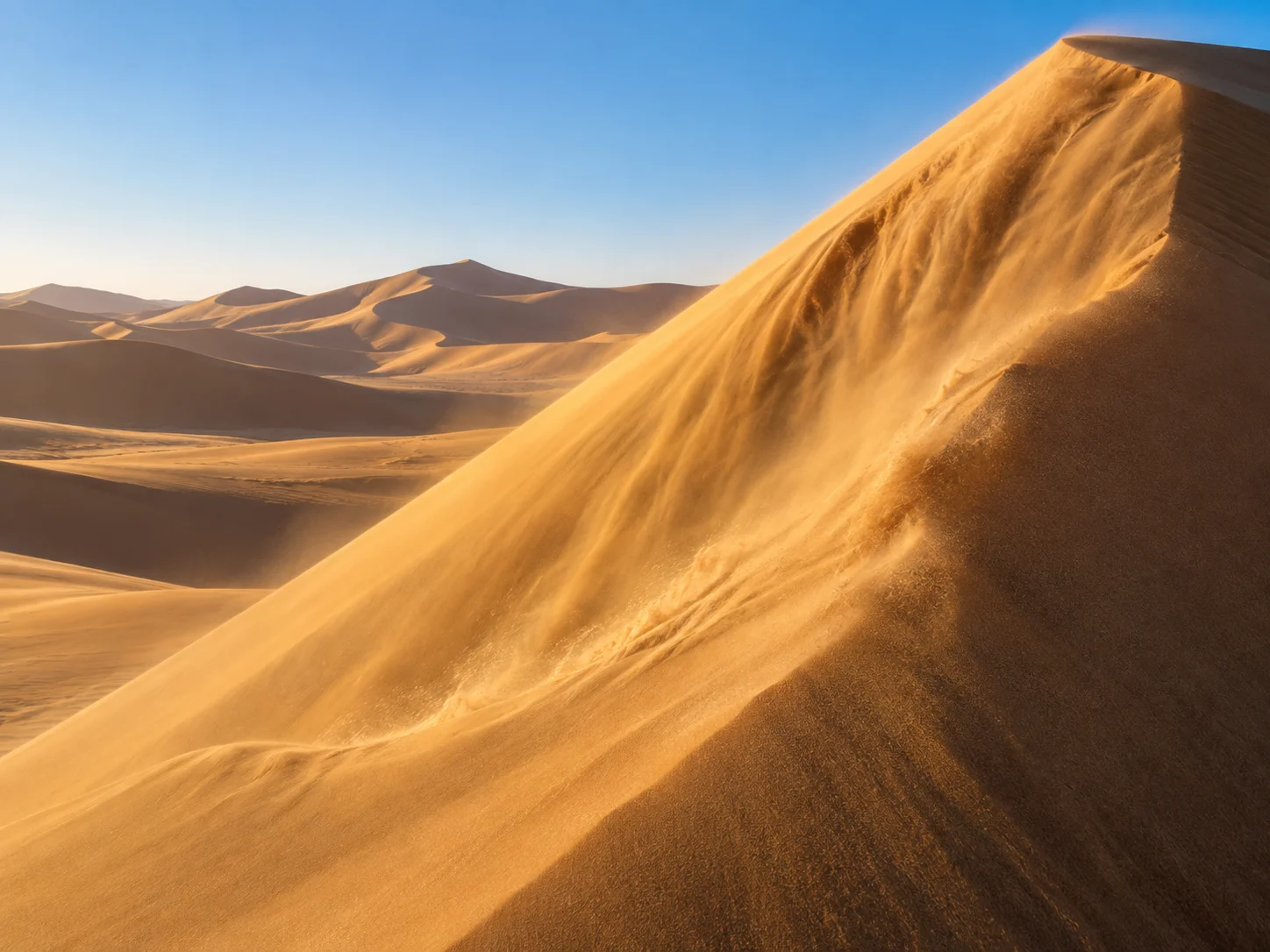 Golden sand sliding down the face of a desert dune