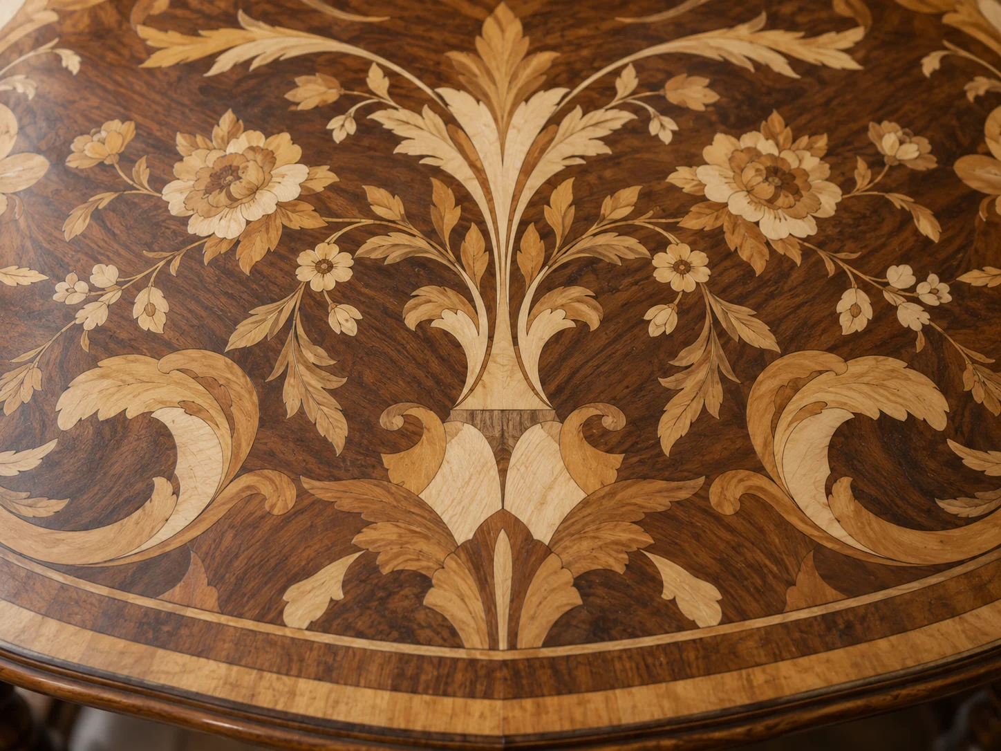 A polished marquetry tabletop with a mirrored floral design in light and dark wood