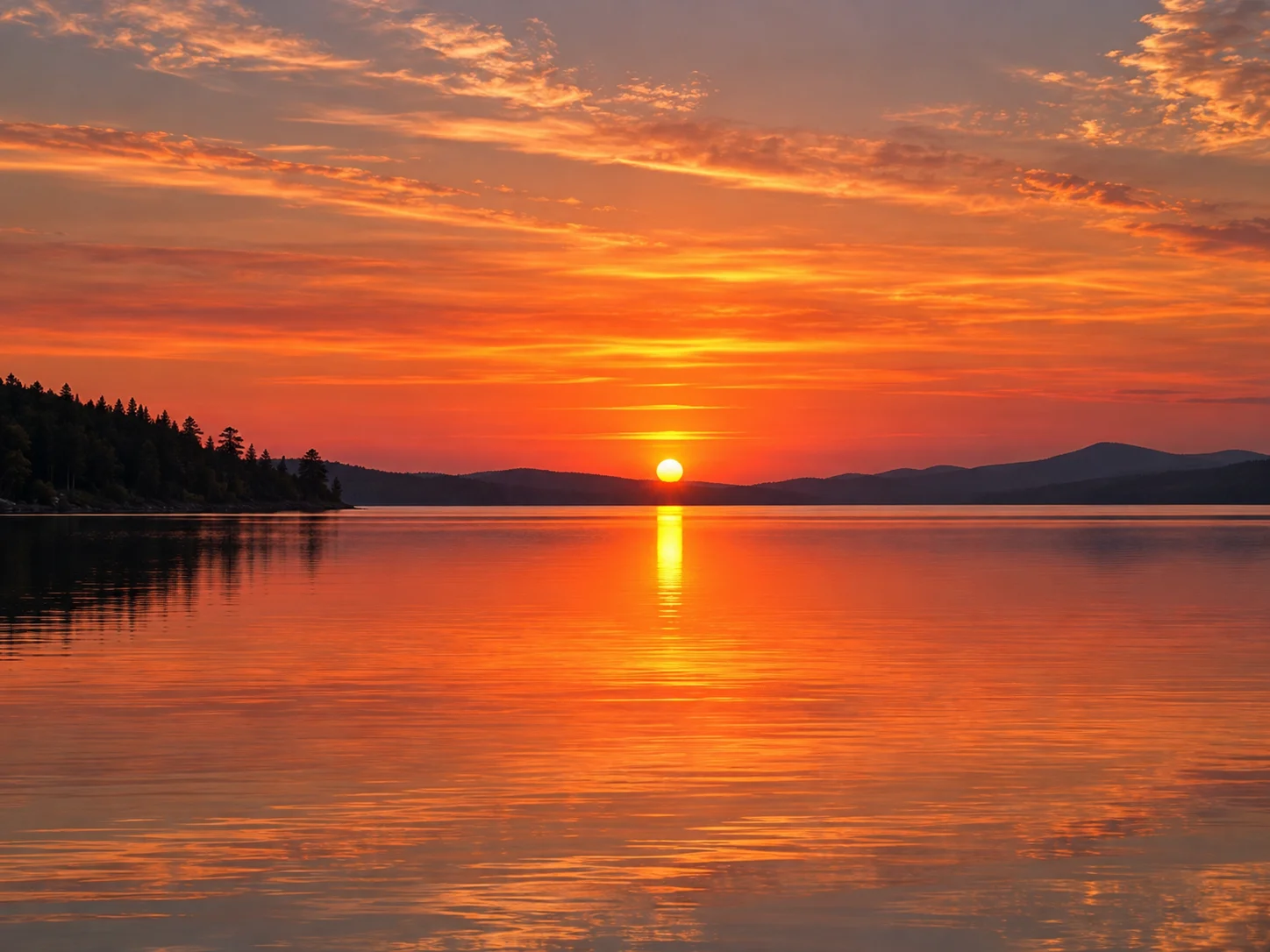 A vivid orange and coral sunset reflected across a calm lake