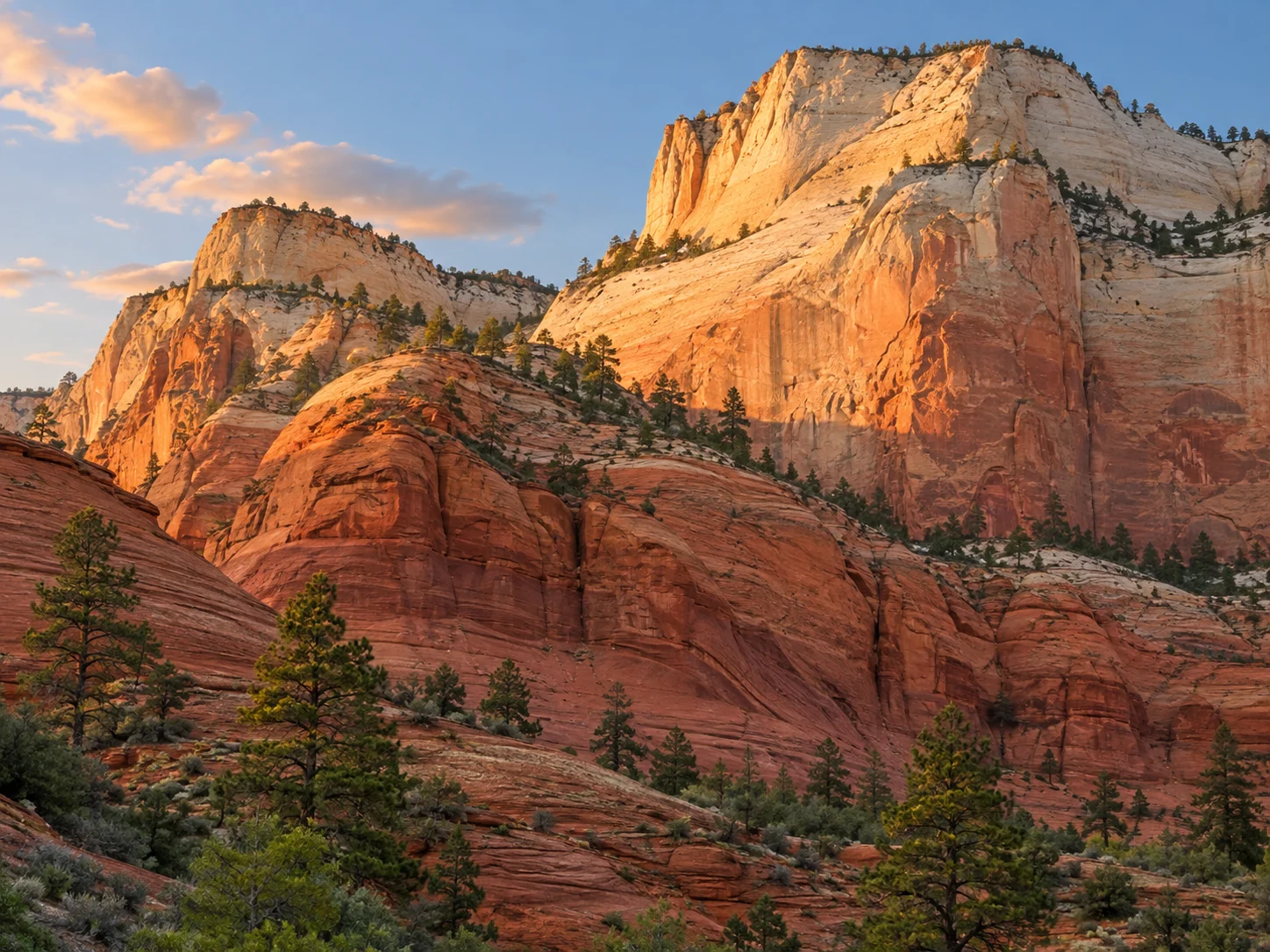 Rounded sandstone cliffs in bands of red, salmon, gold and pale cream