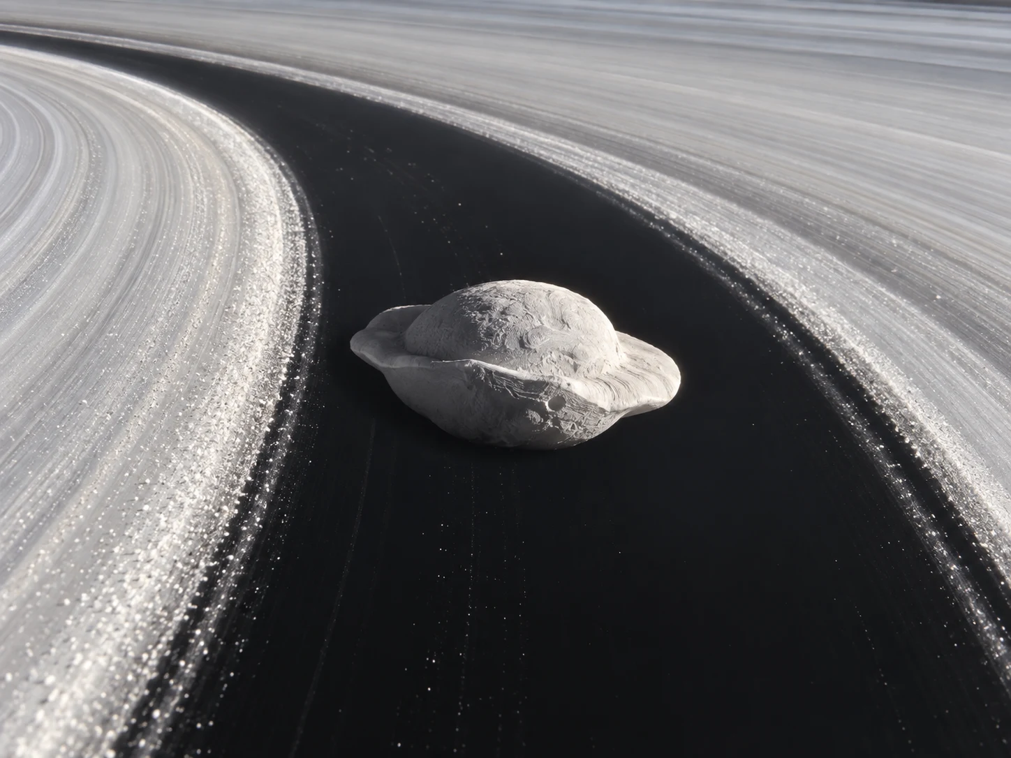 The small ravioli-shaped moon Pan traveling through a dark gap in Saturn's bright rings