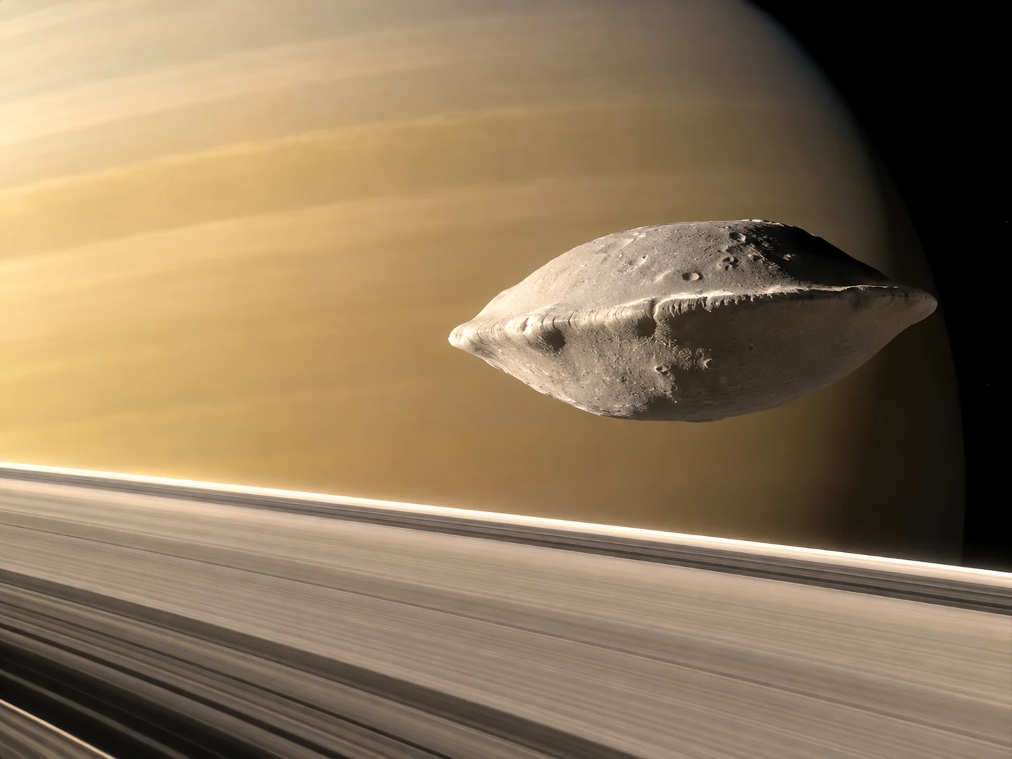 The small moon Atlas with a wide pointed equatorial rim above Saturn's rings