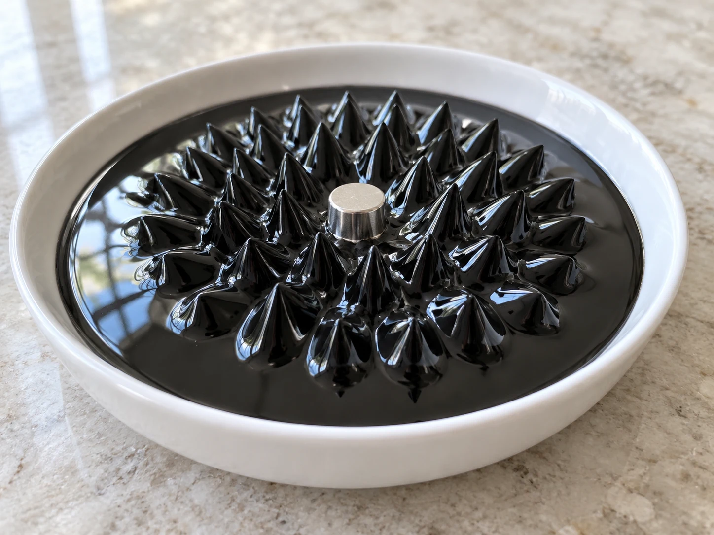 Black ferrofluid forming many glossy spikes around a silver magnet